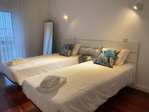 two beds in a hotel room with towels on them at Beach Front with Rooftop in Vila do Conde
