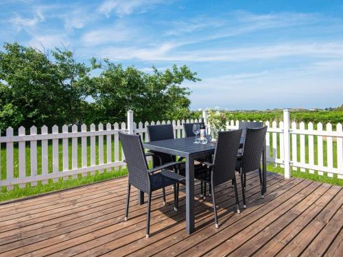 a table and chairs on a deck with a fence at 6 person holiday home in Ringkøbing-By Traum in Søndervig
