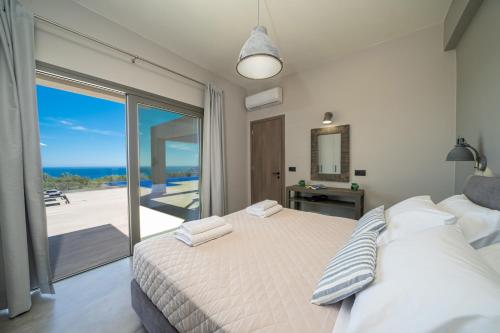 een slaapkamer met een bed en uitzicht op de oceaan bij villa Shades of blue in Trapezaki