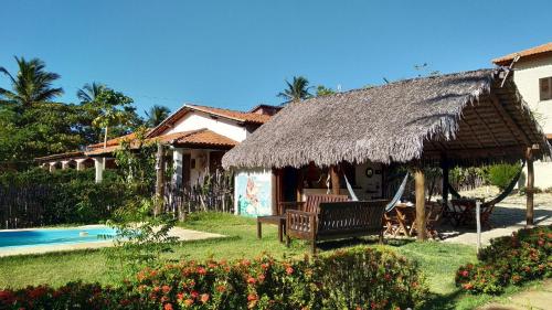 a house with a thatch roof and a swimming pool at Pousada Eolos in Barra Grande