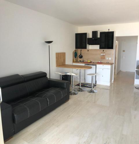un salon avec un canapé noir et une cuisine dans l'établissement Marina06, à Villeneuve-Loubet