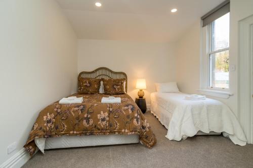 a white bedroom with a bed and a window at Inner City Executive Living on Stuart Street in Dunedin