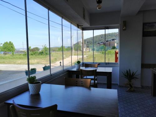 a room with tables and chairs and large windows at Eceabat Doğa Pansiyon-Hotel in Eceabat