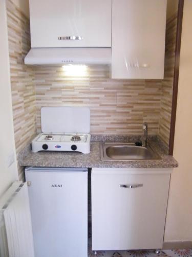 una pequeña cocina con armarios blancos y fregadero en Casa Buenos Aires, en Massa Lubrense