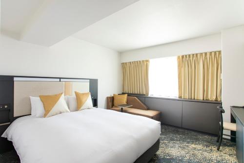 a hotel room with a large bed and a desk at Cross Hotel Osaka in Osaka