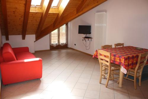 a living room with a table and a red couch at Casa Costa del Sol in Molveno
