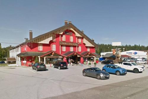 a large red building with cars parked in a parking lot at Magnifique Studio de 20m2 pour 1 à 4 personnes in Les Rousses