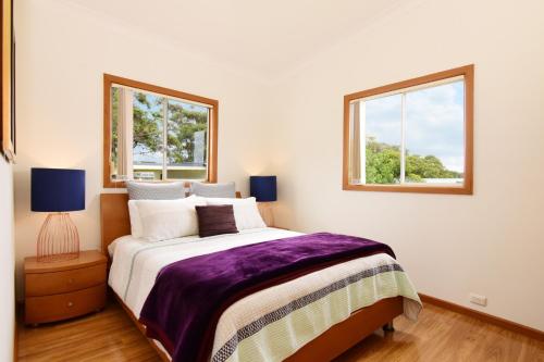 - une chambre avec un grand lit et 2 fenêtres dans l'établissement LAKE146C - Casa Iolanda, à Culburra Beach