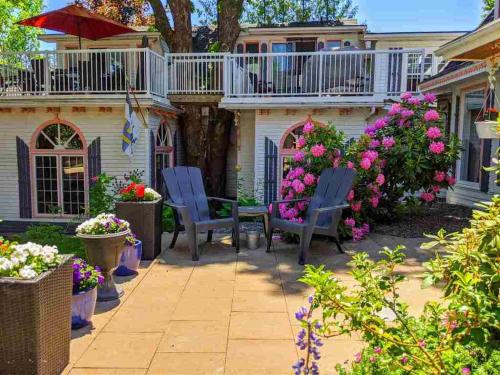 a patio with chairs and flowers in front of a house at Gingerbread House Inn - We Are Open - Winter, Spring, Summer and Fall in Wolfville