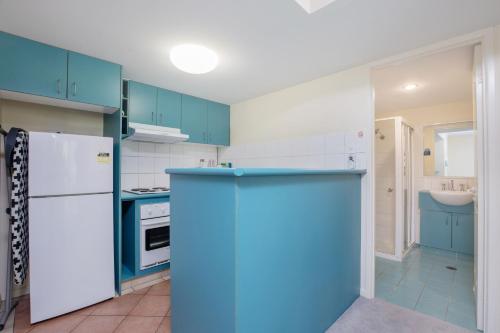 Una cocina con gabinetes azules y un refrigerador blanco. en Surfers Beach Resort One, en Gold Coast