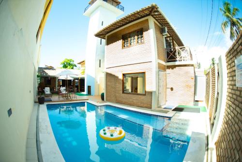 a swimming pool with a toy boat in front of a house at Pousada Panorama in Praia do Frances