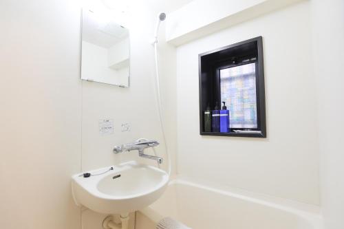 a white bathroom with a sink and a window at SUMIYOSHI APARTMENT Hotel 住吉アパートメントホテル in Fukuoka