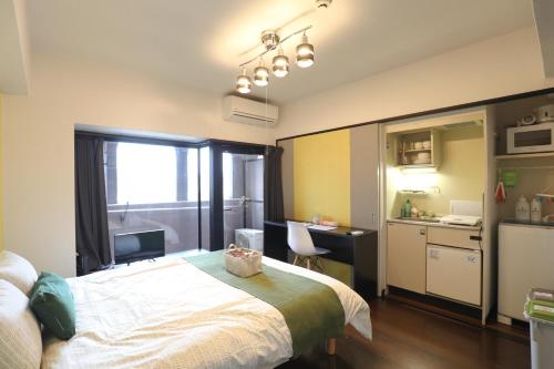 a bedroom with a bed and a desk and a kitchen at Sumiyoshi Apartment in Fukuoka