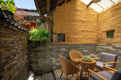 a patio with chairs and a table and a brick wall at Yangshuo Secret Garden in Yangshuo