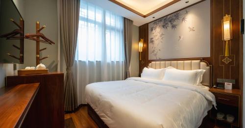 a bedroom with a large white bed and a window at Pierr Palace Hotel (Beijing Nanluo Guxiang) in Beijing