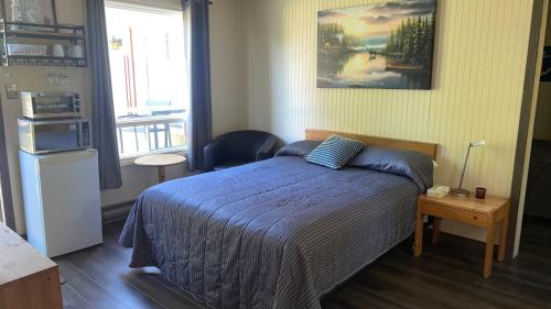 a bedroom with a bed with a blue comforter at Auberge et Chalets sur le Lac in Lac-Mégantic