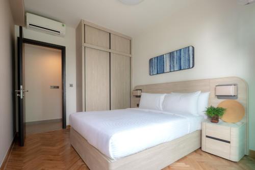 a bedroom with a white bed with a plant on a table at Somerset Feliz Ho Chi Minh City in Ho Chi Minh City