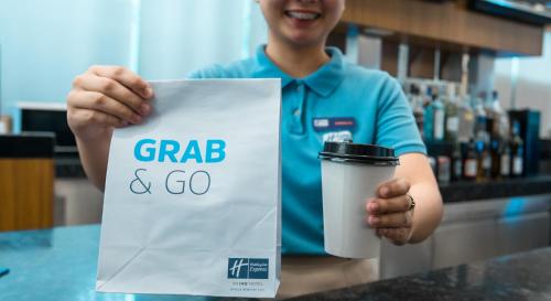 a man is holding a cup of coffee and a sign at Holiday Inn Express Manila Newport City by IHG in Manila