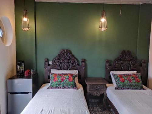 two beds in a room with green walls and lights at Nunõ in San Miguel de Allende