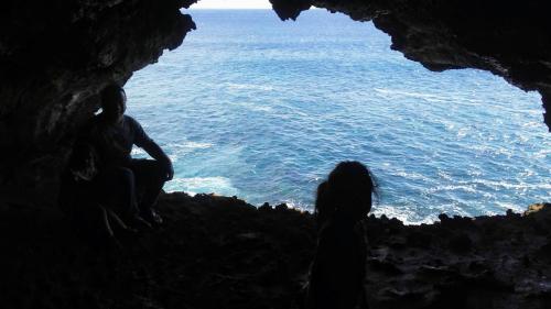 a group of people sitting in a cave looking at the ocean at Cabañas Te Maori in Hanga Roa