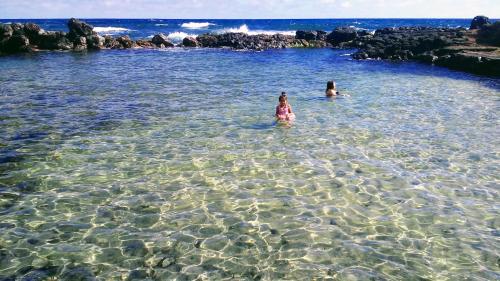 two children swimming in the water at the beach at Cabañas Te Maori in Hanga Roa