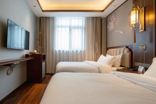 a hotel room with two beds and a flat screen tv at Pierr Palace Hotel (Beijing Nanluo Guxiang) in Beijing