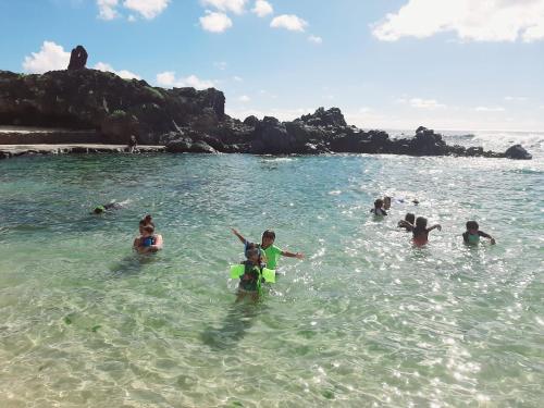 a group of people in the water at the beach at Cabañas Te Maori in Hanga Roa
