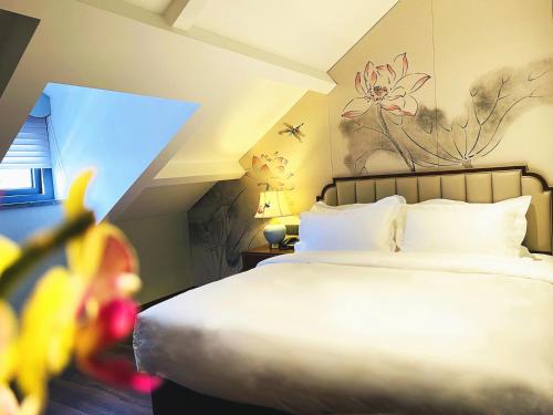 a bedroom with a white bed with a flower painting on the wall at Pierr Palace Hotel (Beijing Nanluo Guxiang) in Beijing