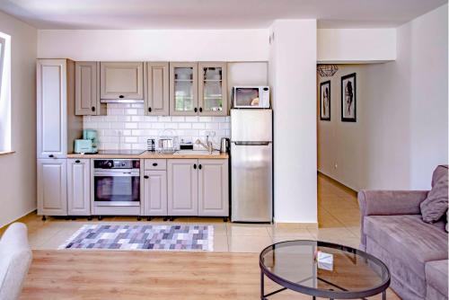 a kitchen with white cabinets and a table in a living room at Apartamenty Kornel in Pobierowo