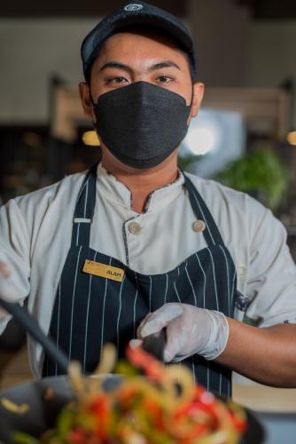 a man with a mask on his face next to a bowl of food at Nava Hotel Tawangmangu in Tawangmangu