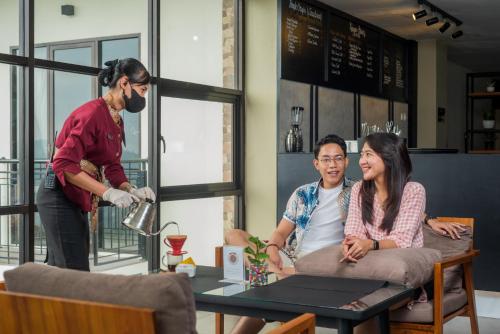 a man standing in a room with two people sitting at a table at Nava Hotel Tawangmangu in Tawangmangu