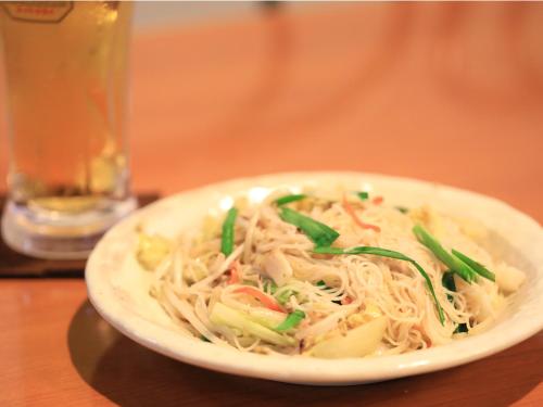 a white bowl of noodles and vegetables on a table at Pension Sea Friend in Tokashiki
