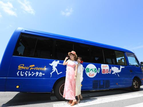a woman standing in front of a bus at Pension Sea Friend in Tokashiki