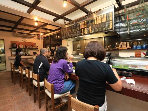 a group of people sitting at a bar in a restaurant at Pension Sea Friend in Tokashiki