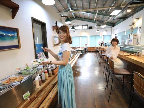 a woman holding a plate of food in a restaurant at Pension Sea Friend in Tokashiki