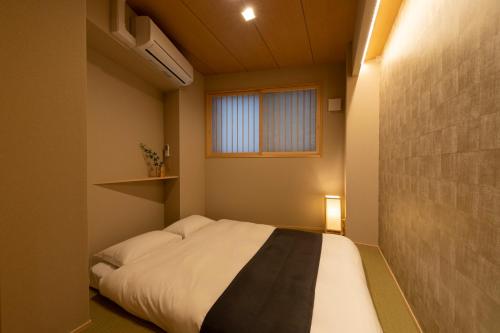 a small bedroom with a bed and a window at Shirakabanoyado - EBISU in Osaka