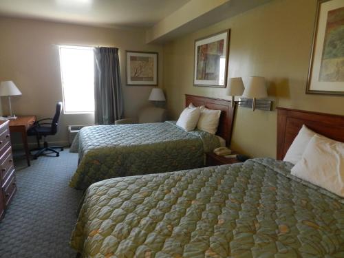 a hotel room with two beds and a desk at Days Inn by Wyndham Downtown St. Louis in Saint Louis