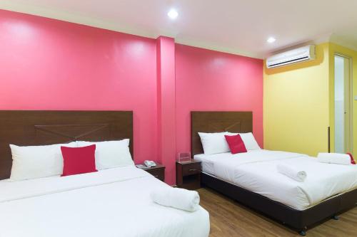 two beds in a room with a pink wall at Hotel Sunjoy9 Bandar Sunway in Petaling Jaya