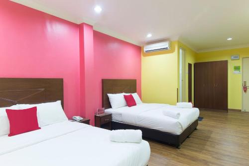 a room with two beds and a pink wall at Hotel Sunjoy9 Bandar Sunway in Petaling Jaya