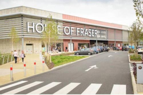 a store front of a building with a parking lot at Chichele House, sleeps 8, Nr Rushden Lakes, allocated parking, corporate welcome in Higham Ferrers
