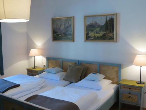 2 Betten in einem Zimmer mit 2 Lampen und Wandmalereien in der Unterkunft Meckyheim in Mayrhofen