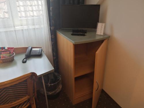 a room with a desk with a television and a phone at Pension am Heusteig in Stuttgart