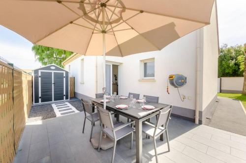 une table avec des chaises et un parasol sur une terrasse dans l'établissement NEW YORK House, à Villejust