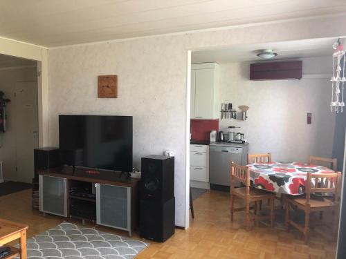 a living room with a television and a table and a kitchen at Apartment with aircondition and sauna in Kuusamo