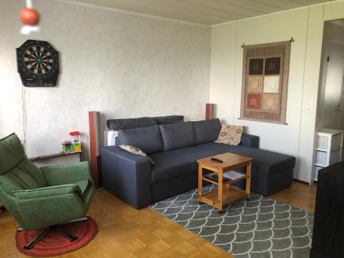 a living room with a blue couch and two chairs at Apartment with aircondition and sauna in Kuusamo