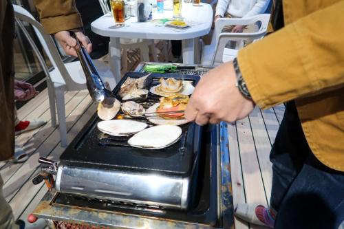 a person is cooking food on a grill at B&B MIKAWA 5 - Villas with BBQ Terrace in Kanazawa