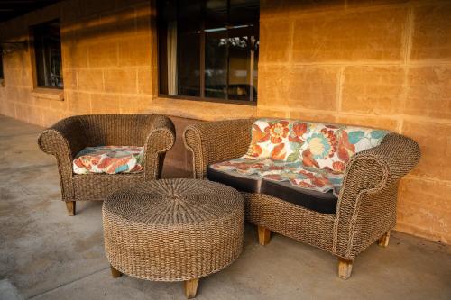 two wicker chairs and a table next to a building at Glen Mervyn Lodge in Mumballup