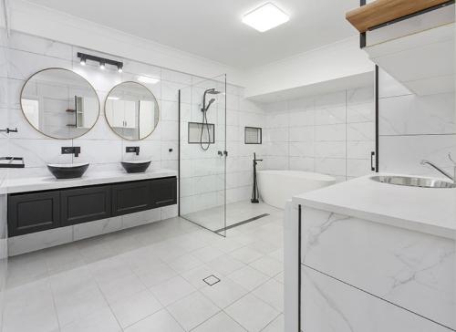 a white bathroom with two sinks and a bath tub at Shellharbour Seaside Escape in Shellharbour