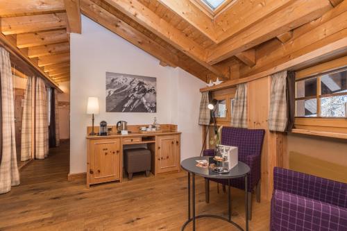 Habitación con tocador y mesa con sillas moradas. en Hotel Bella Vista Zermatt, en Zermatt