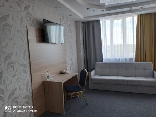KachkanarにあるHotel Pyaterochka Luxのベッド、デスク、ソファが備わるホテルルームです。